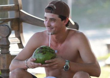 Ex-BBB Fael toma água de coco sozinho na praia